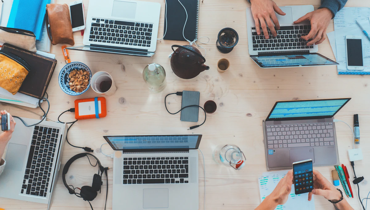 Vista desde arriba de una mesa de trabajo con computadores y un teléfono